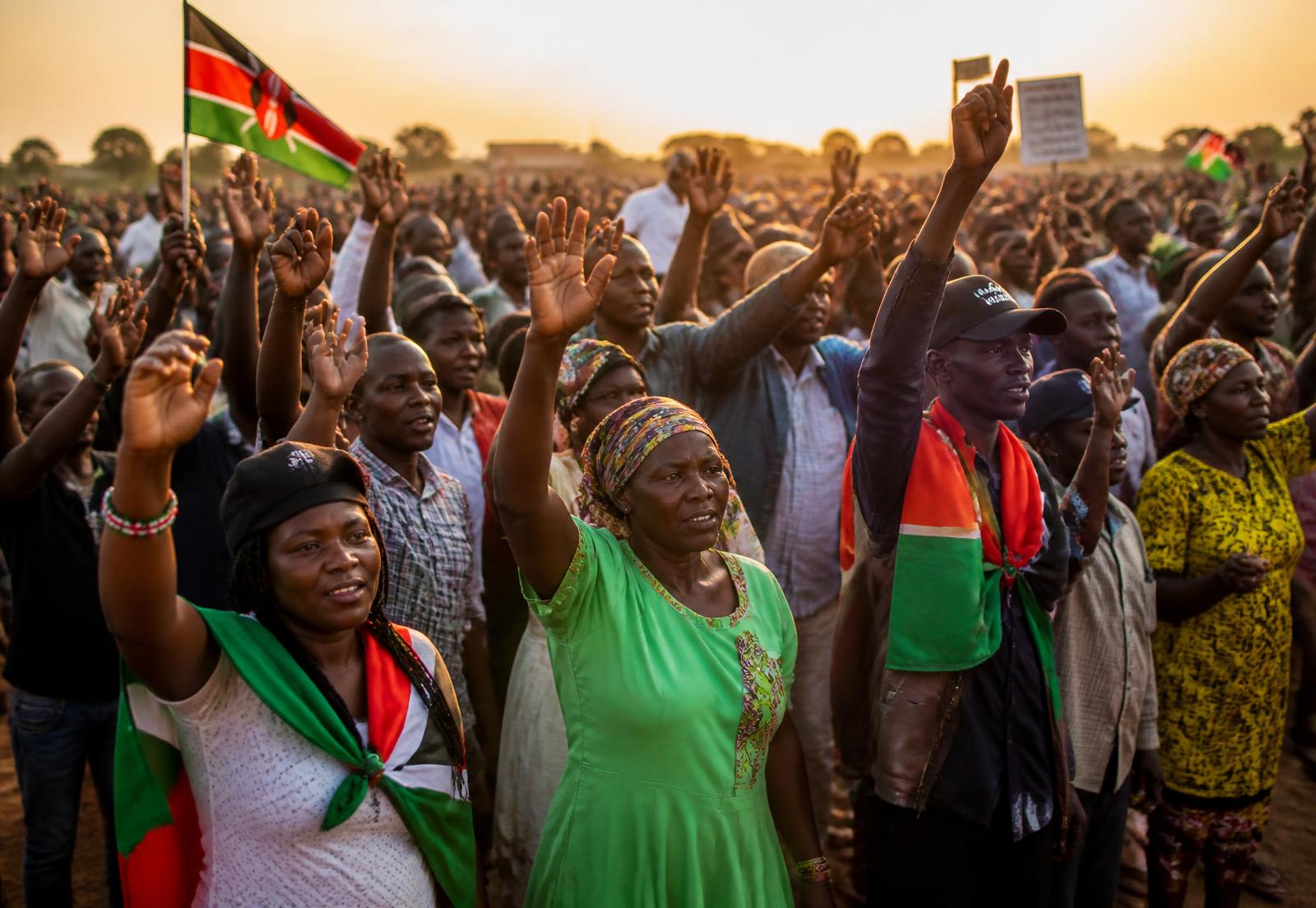 Kenyan citizens raising their hands at a peaceful community rally